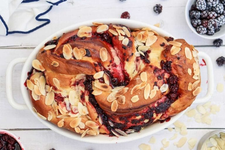 Blackberry Swirl Bread topped with sliced almonds in a white baking dish.