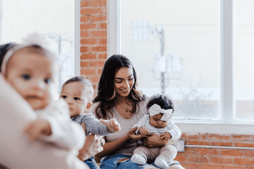Mother holding a baby while sitting with other moms and infants.