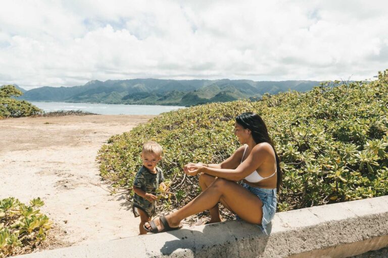 Mom and toddler enjoying a sunny beach day, a reminder of why a well-planned toddler packing list matters.