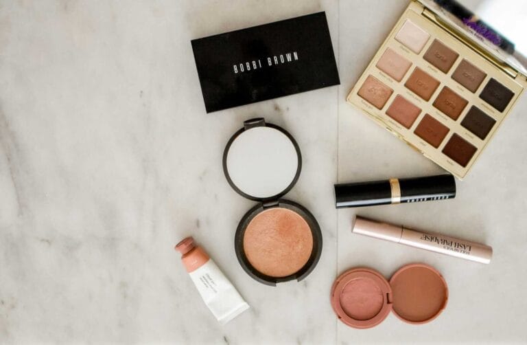 Flatlay of neutral-toned makeup products used in makeup workshops.