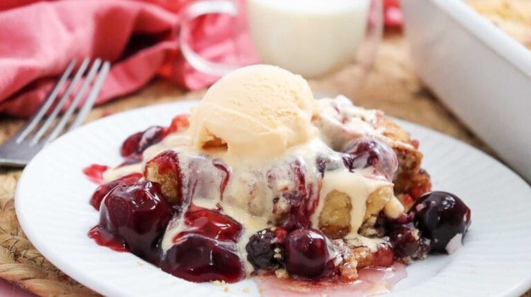 Cherry dump cake topped with vanilla ice cream and cherry sauce.
