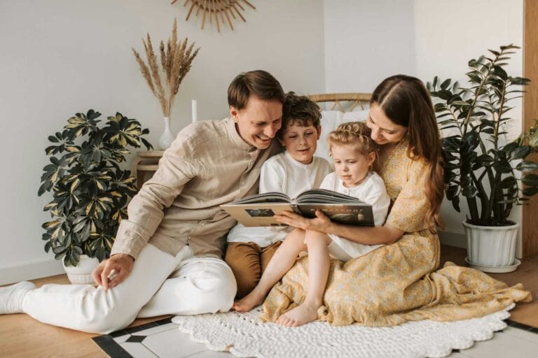 Family sitting together in neutral outfits reading a book, inspiring What to Wear for Family Photoshoot ideas.