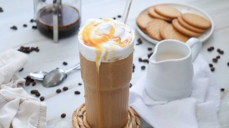Tall glass of healthier Starbucks inspired caramel iced coffee topped with whipped cream and caramel drizzle.