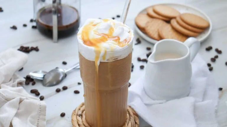 Tall glass of healthier Starbucks inspired caramel iced coffee topped with whipped cream and caramel drizzle.