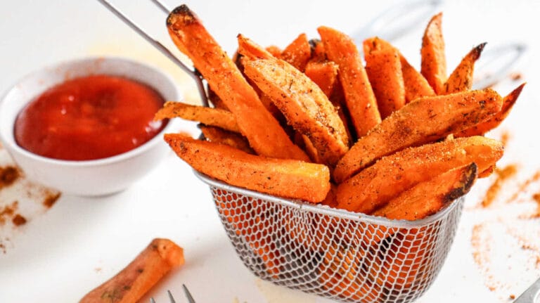 Crispy air fryer sweet potato fries in basket with ketchup